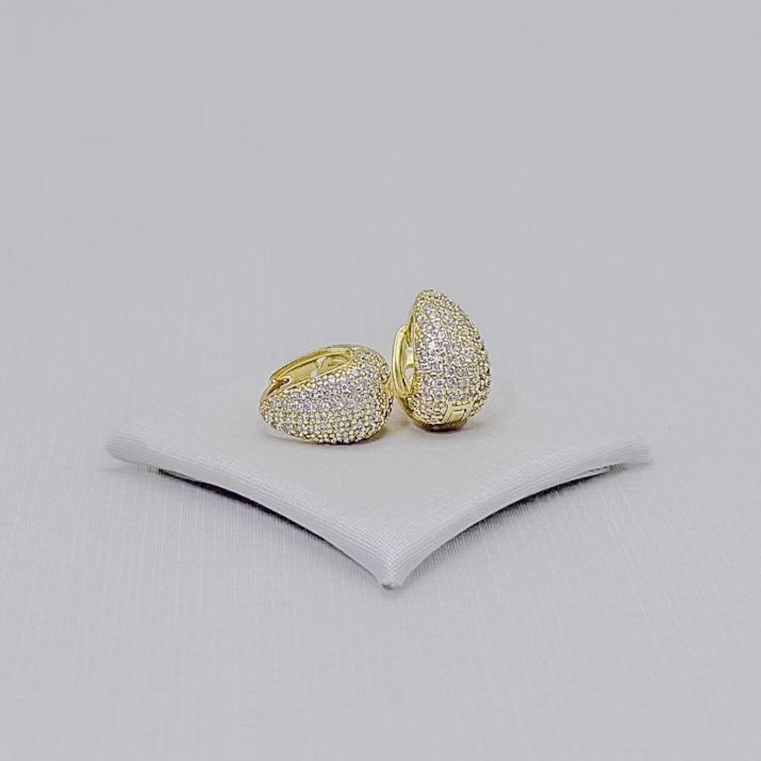 05.3291.1.O - Argola em formato de garra larga com frente cravejada e parte de atrás com flor vazada, tamanho 13x9mm. Argola banhada em ouro.