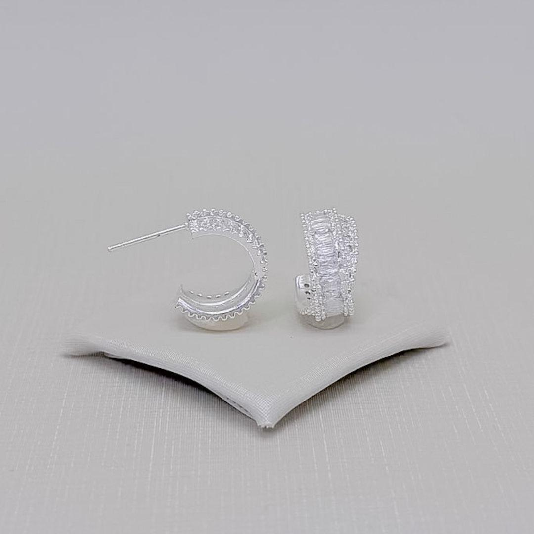 05.3305.1.S - Argola de tarraxa em fio largo com uma coluna de baguete com borda spike e outra coluna simples. Argola banhada a prata.