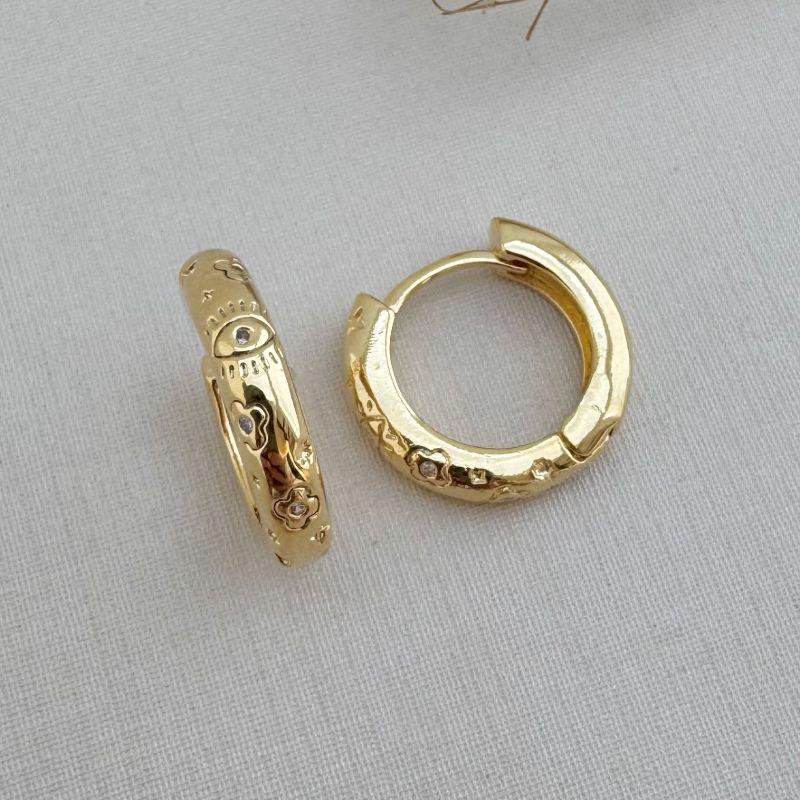 05.2908.1.O - Argola circular de tubo oval com desenhos de flores e olho com micro zirconias espalhadas