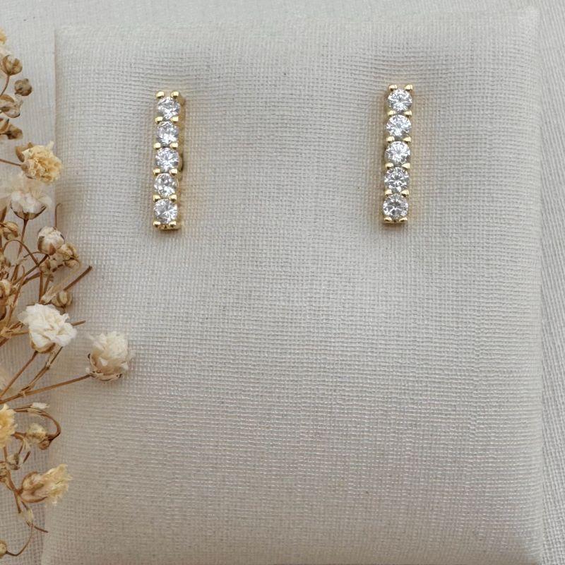 07.2680.1.O - Brinco um traço cravejado de cinco pedras em riviera garras