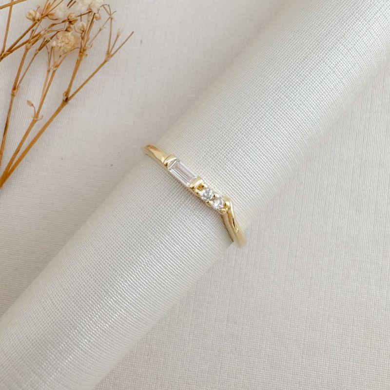 03.2474.1.O - (22) Anel de aro liso com central de pedra baguete seguida de duas zircônias